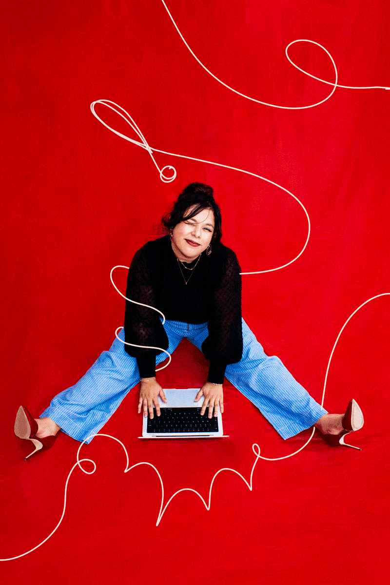Vicky, founder of Alma Co., seated at a laptop against a red backdrop overdrawn with a looping white line.