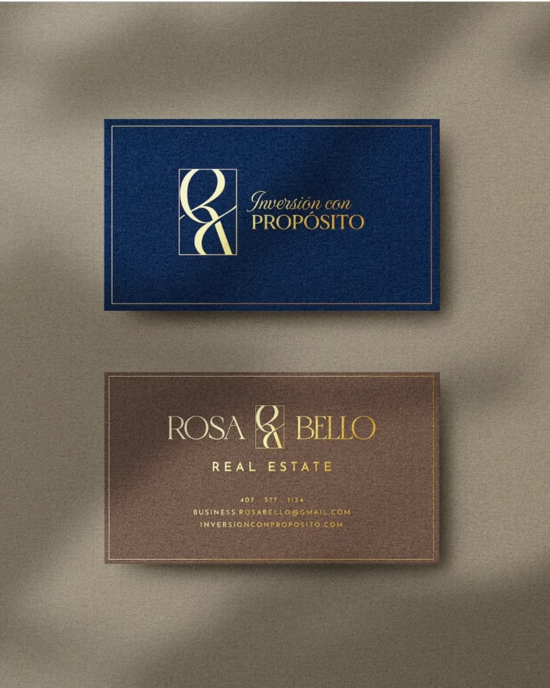 Business cards — the gold monogram with "Inversión con Propósito" on navy, and a bronze card carrying the Rosa Bello Real Estate wordmark and contact details.